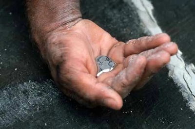 Uma mão segurando uma pequena quantidade de mercúrio, com a superfície ao redor coberta de pó.