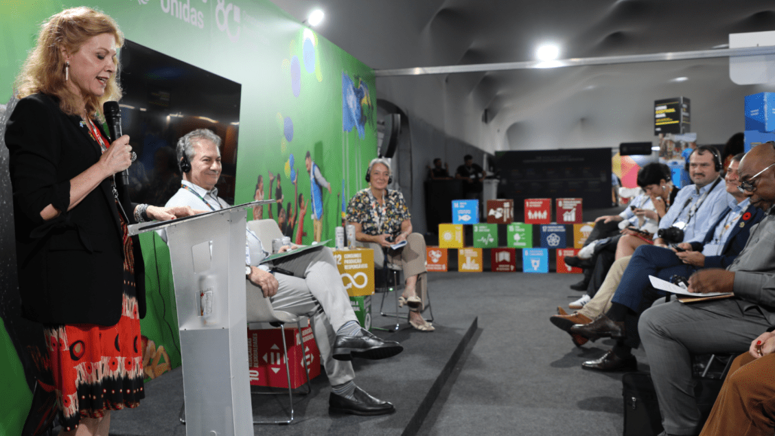 Evento da ONU com apresentadores e participantes discutindo temas de desenvolvimento sustentável, com foco na proteção ambiental e inclusão social.