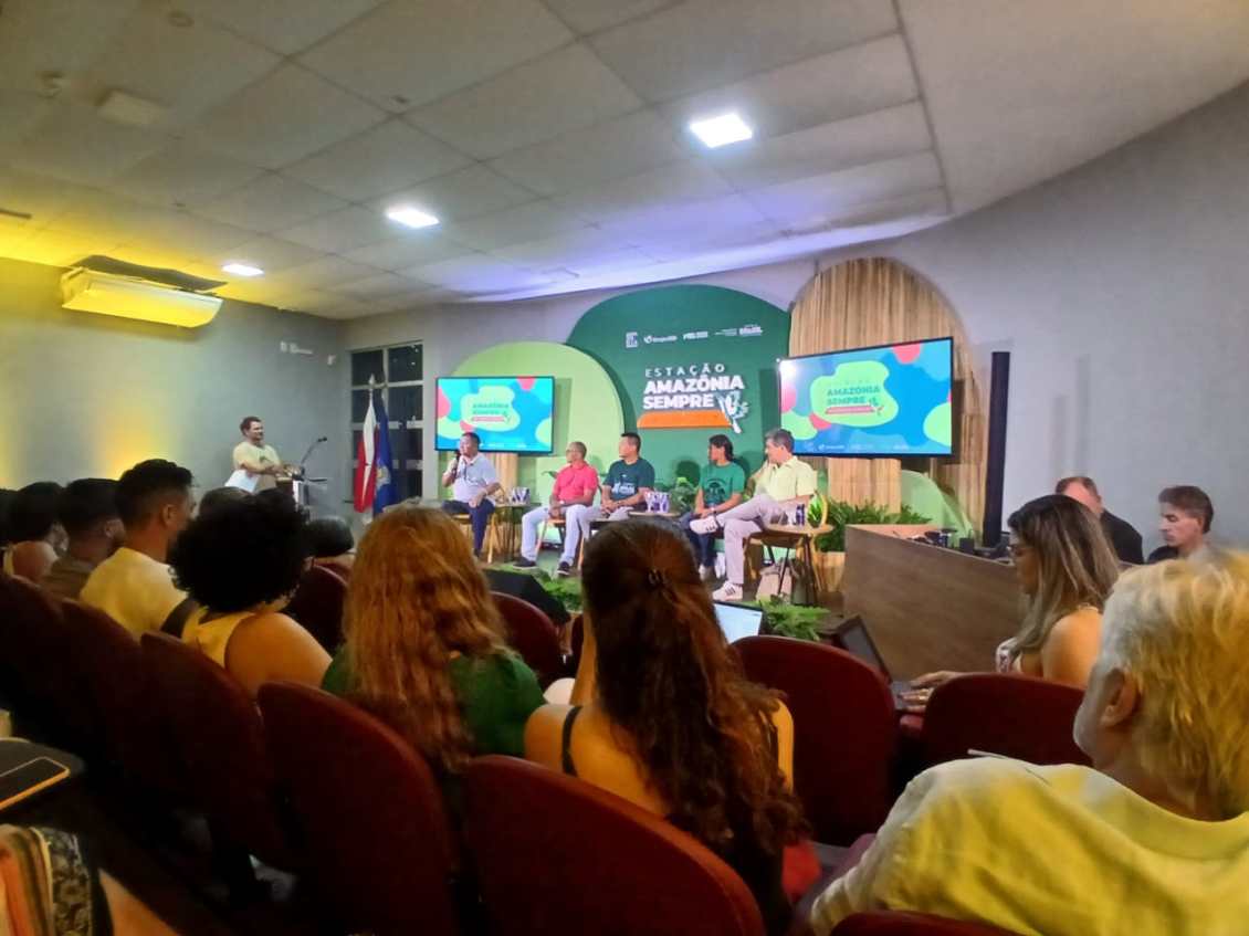 Evento na COP30 sobre o Projeto Amazônia Revelada, com panelistas discutindo a história e a cultura da Amazônia, em uma sala iluminada e decorada com elementos naturais.