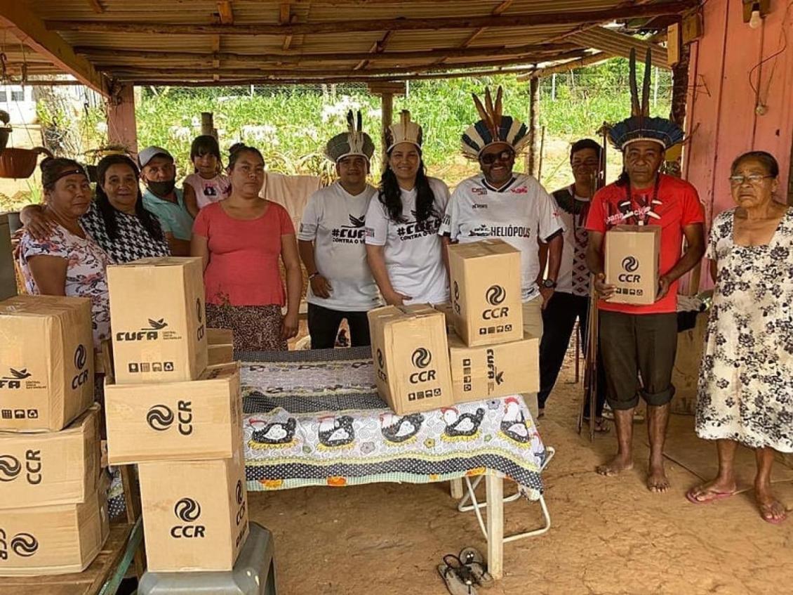 Grupo de pessoas em uma comunidade com caixas de doações da CUFA e CCR, mostrando solidariedade e apoio mútuo.