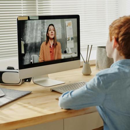 photo of child sitting by the table while looking at the imac